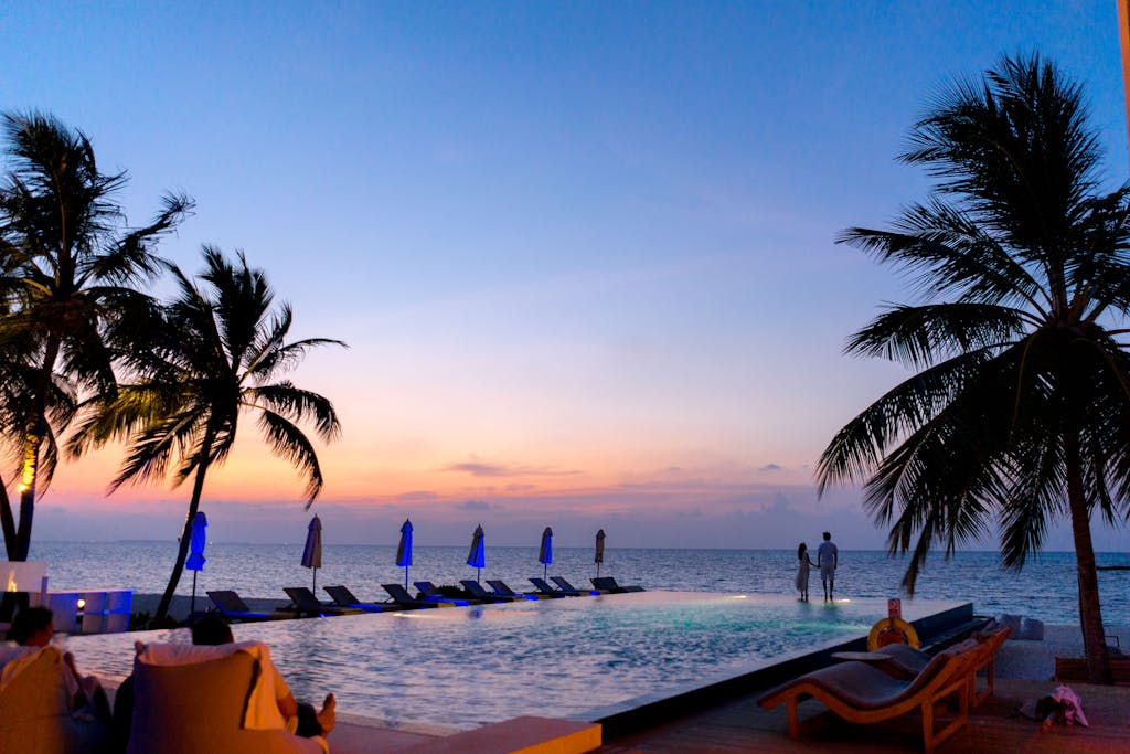 A luxury resort terrace with outdoor dining at golden hour overlooking a tropical landscape representing plant-forward luxury travel accommodations