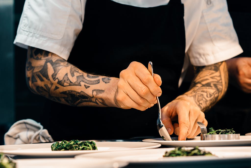 A professional chef carefully plating a plant-based dish in a luxury restaurant open kitchen demonstrating the artistry of vegetarian fine dining
