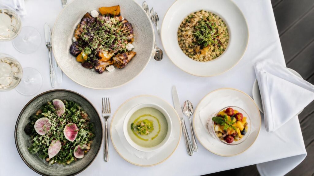Plant-based dishes on a white tablecloth, comparing vegetarian cruise dining across cruise lines